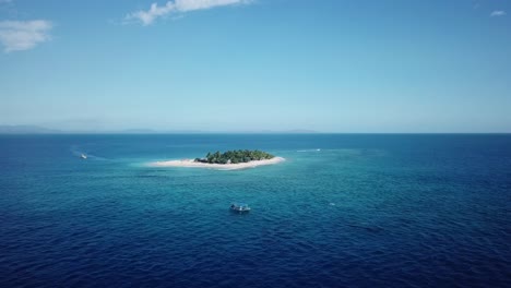 disparo de drones, volando desde lejos hacia un barco con la isla del mar del sur como fondo en fiji