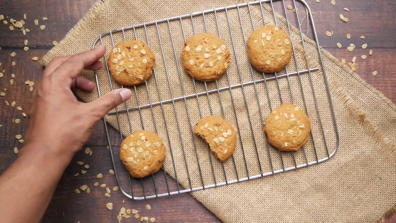 Hand picking a bite of oatmeal cookies from cooling rack