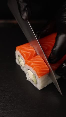 el chef está cortando un rollo de sushi de salmón.