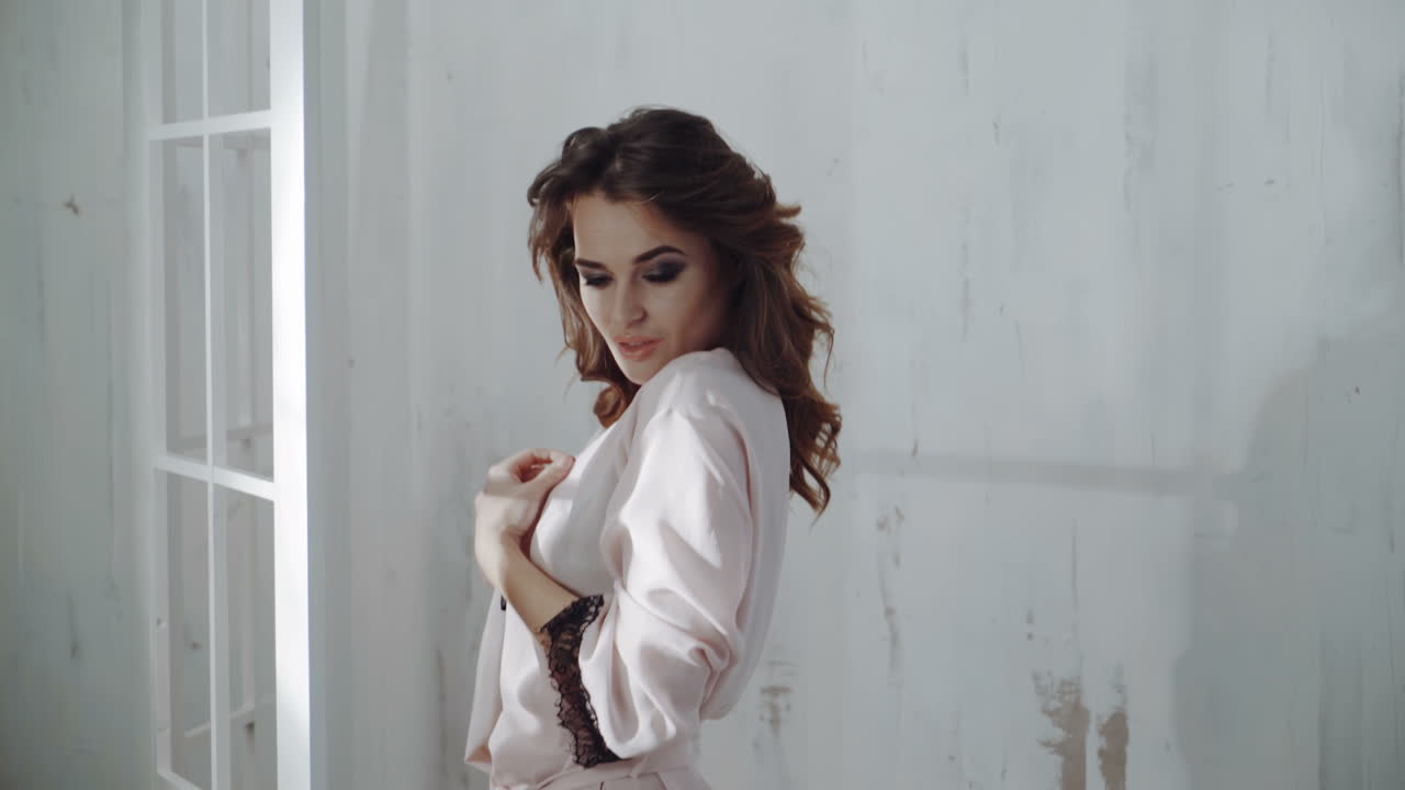 Sexy beautiful brunette woman posing in pink dressing gown. A girl with a thin thin body.