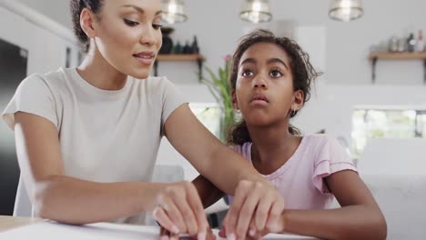 Happy-african-american-mother-and-daughter-reading-braille,-slow-motion