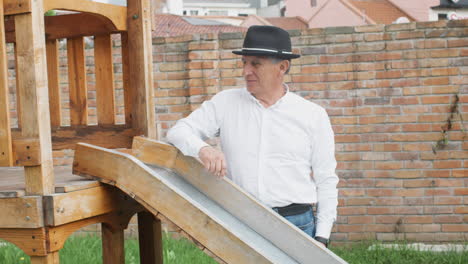 a tender moment between grandfather and grandson as they play together in a wooden playhouse with a slide in the backyard.