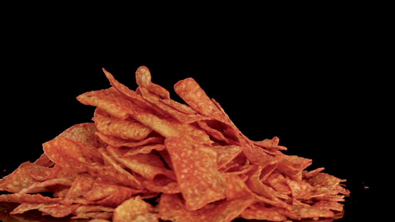 Golden nacho tortilla chips rotate smoothly under studio lighting, revealing texture and seasoning details