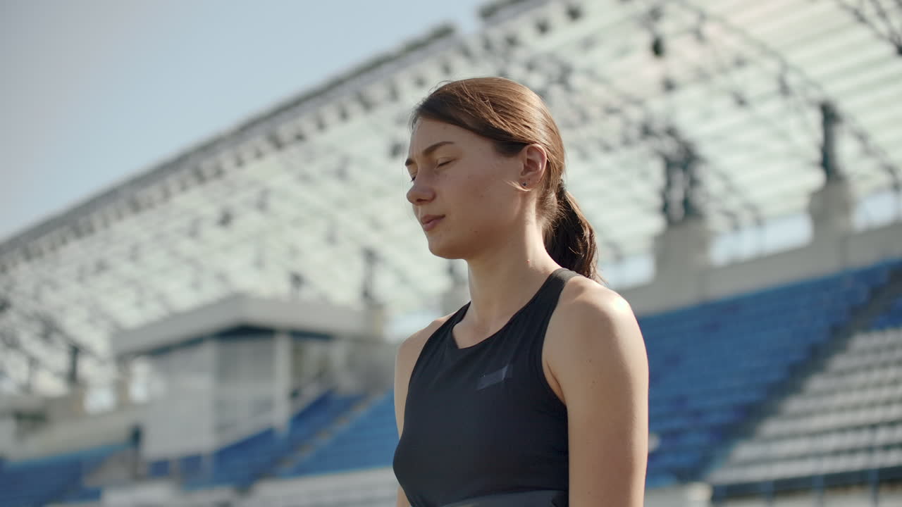 느린 동작: 운동선수 여성이 달리기 트랙에서 출발 블록에서 기다리고 있습니다.