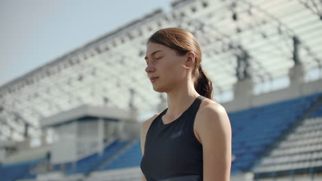 느린 동작: 운동선수 여성이 달리기 트랙에서 출발 블록에서 기다리고 있습니다.