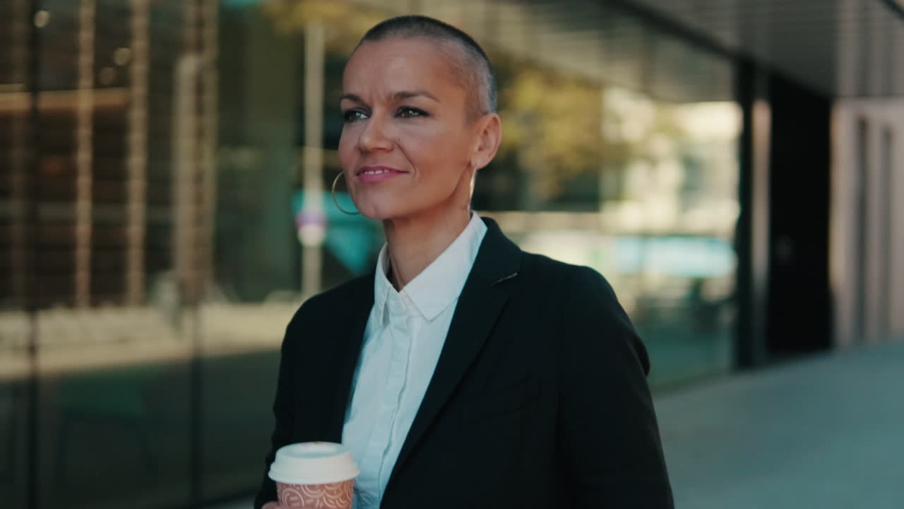 Sikker forretningskvinde, der går med en kaffekop i et urbant miljø