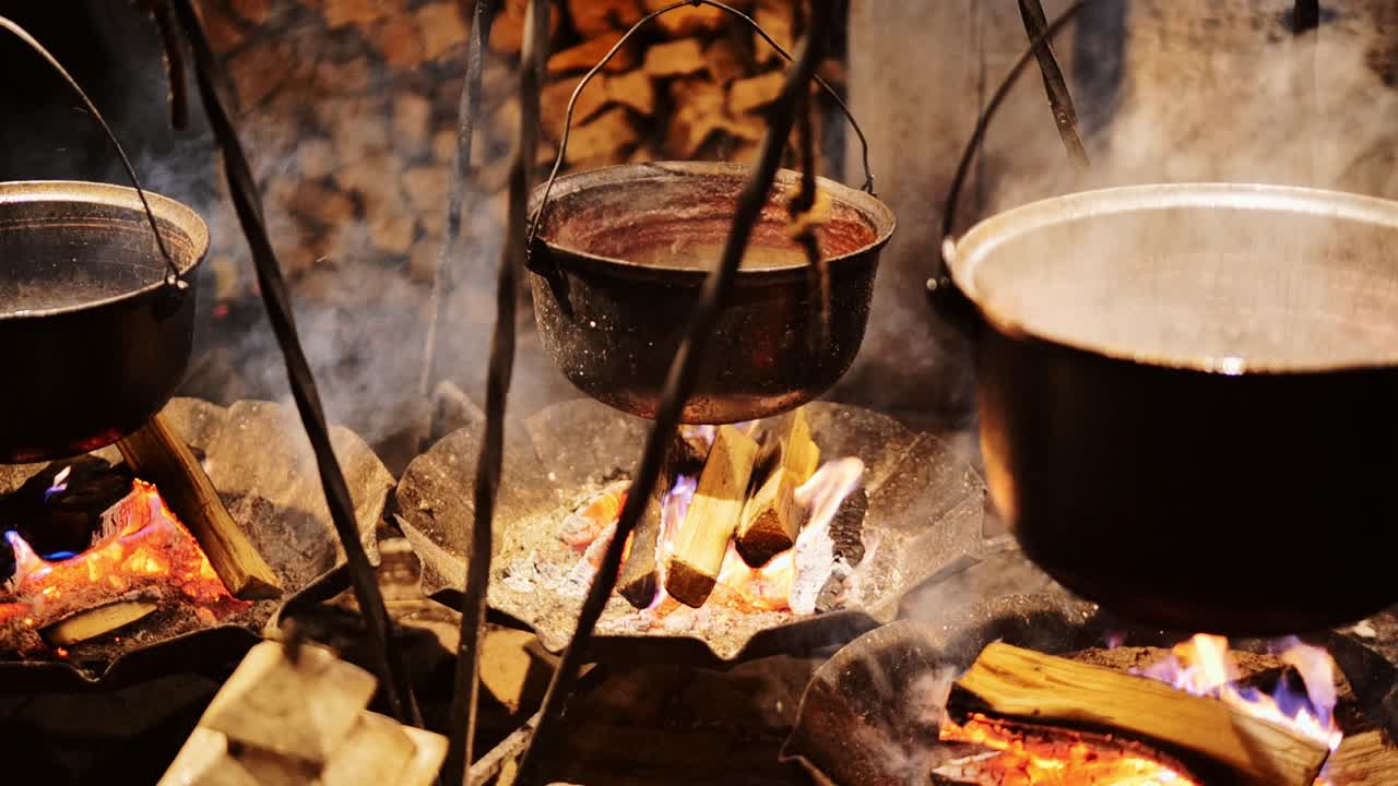 Traditional festive outdoor cooking with steaming pots on open flames, 4K