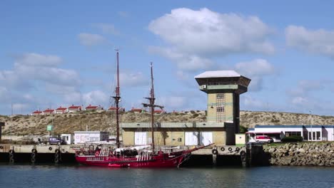 wide shot of old ship docking at port near a command tower