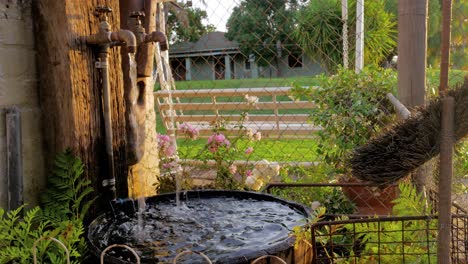 Wasserspiel-Mit-Alten-Wasserhähnen-Und-Wasser,-Das-In-Das-Becken-Eines-Halben-Weinfasses-Fällt