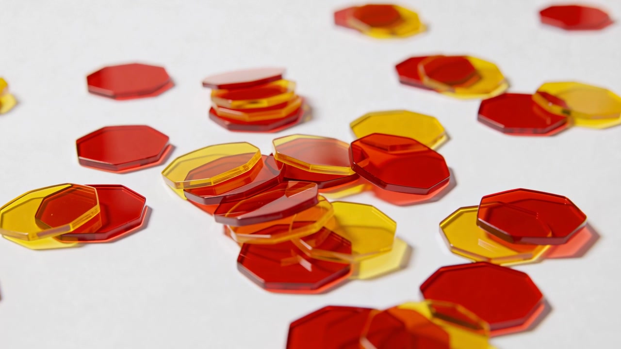Panning camera gliding over white table, revealing red yellow octagonal tokens and center stack