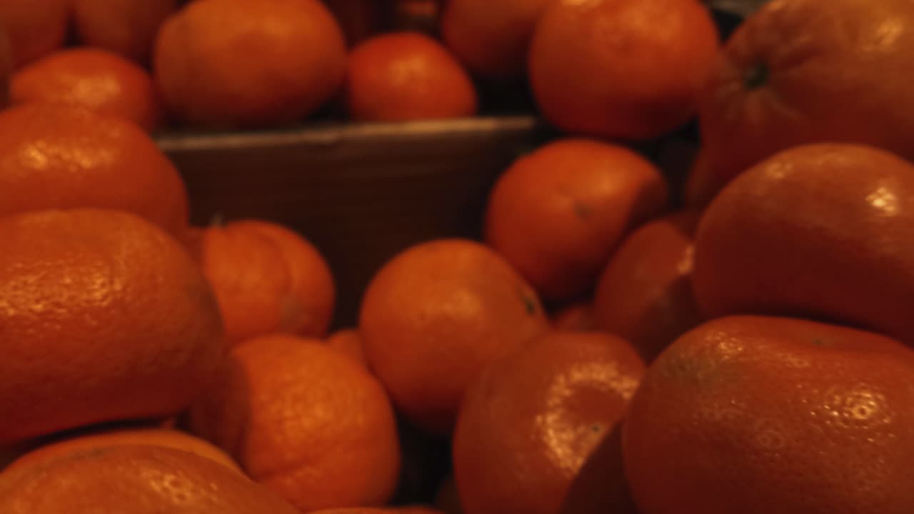 Vista de perto de tangerinas frescas e suculentas empilhadas em um caixote para venda em um supermercado local, exibindo a cor laranja vibrante e a textura da fruta cítrica com um fundo desfocado.
