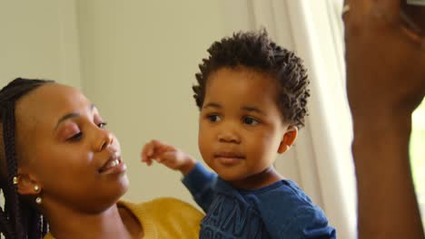 Front-view-of-young-black-mother-holding-her-baby-in-a-comfortable-home-4k