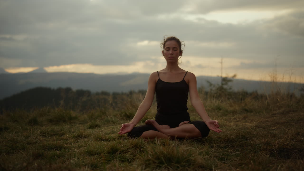 mujer meditando en las montañas al atardecer. niña sentada en la postura de loto en el suelo