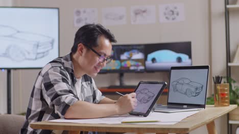 side view of asian male celebrating success drawing new car design concept on a tablet in the studio with tv and computers display 3d electric car model