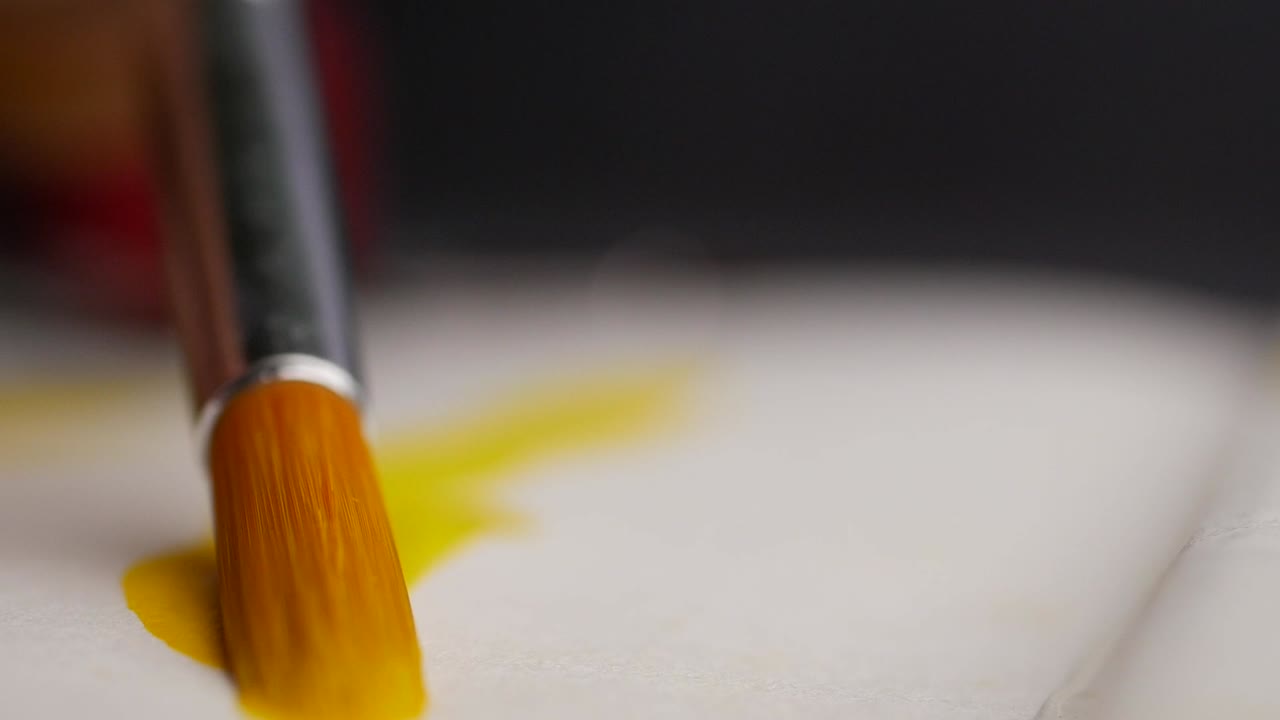 노란색 페인트를 적용하는 페인트 브러쉬의 클로즈업