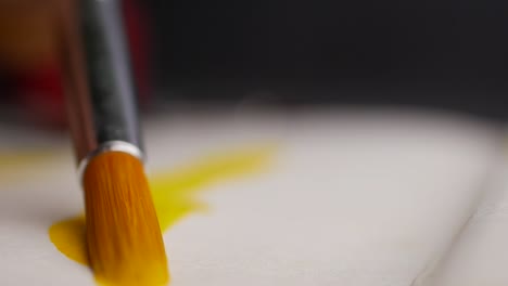 close-up of a paintbrush applying yellow paint