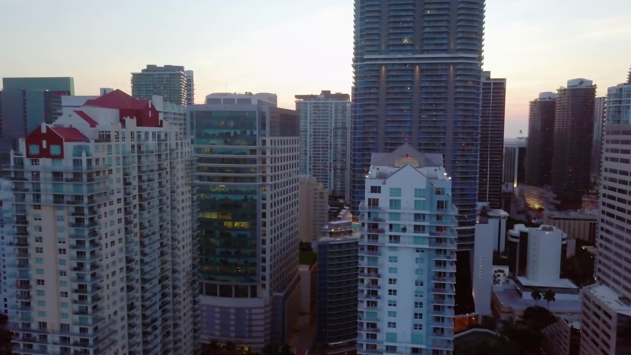 Aerial view rising close to high rise buildings, in the Brickell district, during sunrise, in Miami, Florida, USA - tracking, drone shot