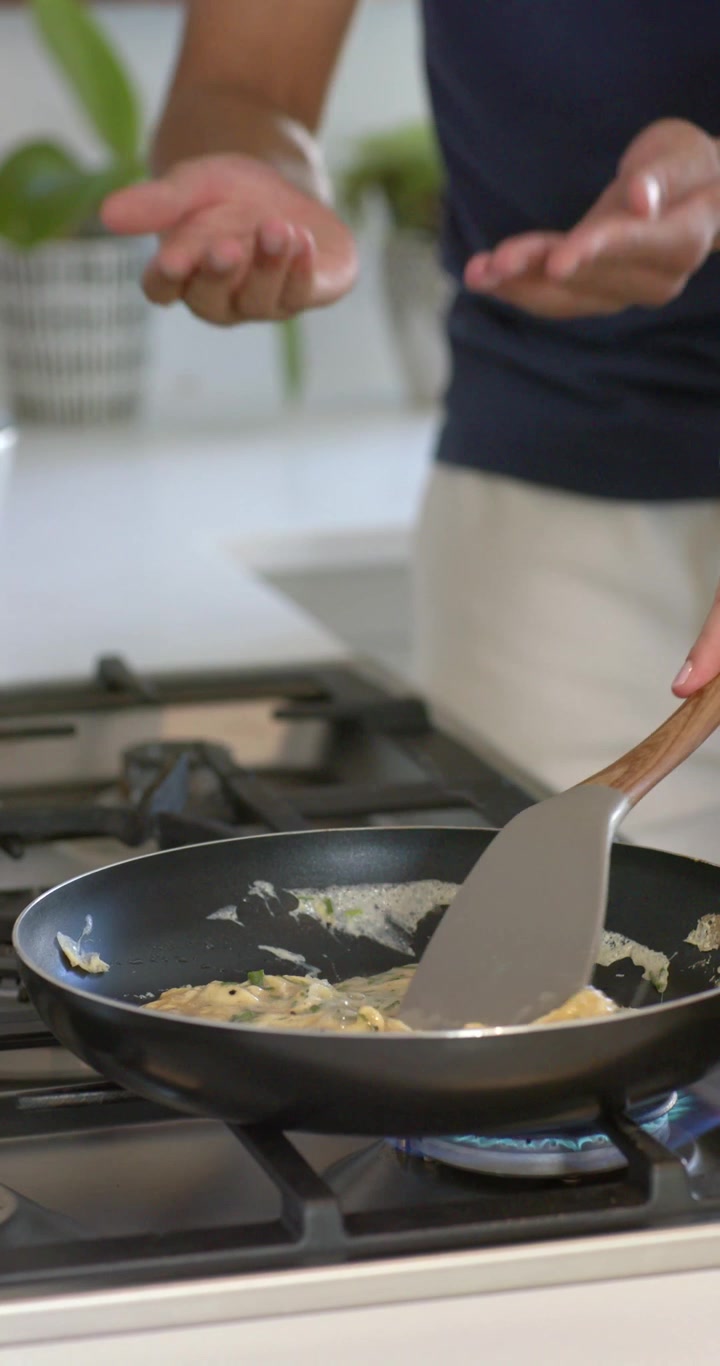 Vertical video: Couple folding eggs on gas flame as man using spatula while woman checking doneness