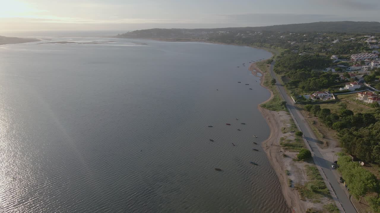 Laguna con la spiaggia e l'oceano all'orizzonte e case immerse nella natura.