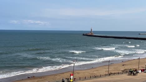 scenic view of roker beach and sunderland pier with waves crashing on shore and sunny sky