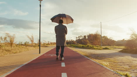man walks with an umbrella on a sunny day