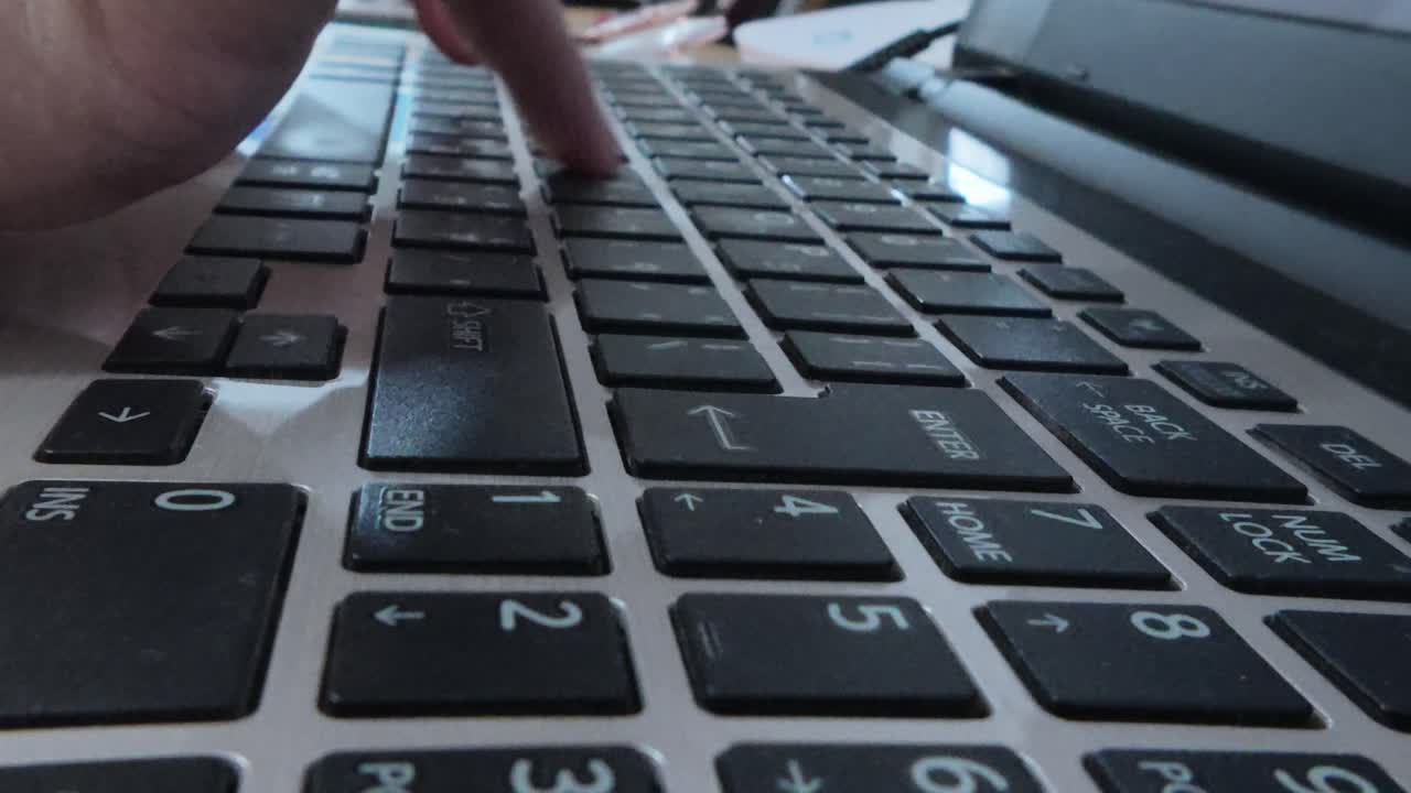 Side close-up of a writer's hands engaged in typing on a laptop, focused on content creation.