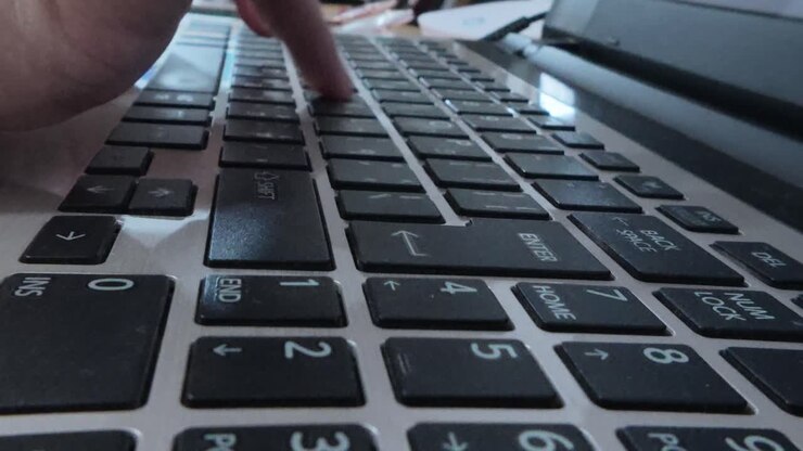Side close-up of a writer's hands engaged in typing on a laptop, focused on content creation.
