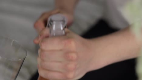 Opening-bottle-of-sparkling-wine-and-pouring-it-into-glass,-closeup