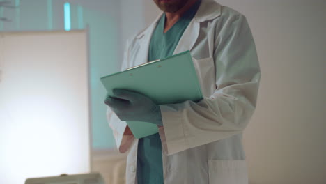 porträtarzt hält die schreibtafel und macht notizen in der intensivstation des krankenhauses.