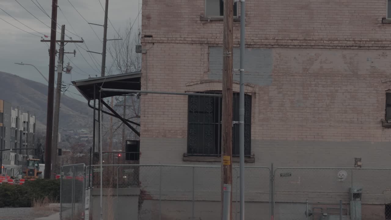 Toma lenta y constante de un edificio industrial de ladrillo envejecido con tendido eléctrico e infraestructura urbana.
