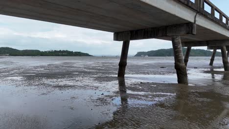 aerial footage of a pier in phuket, thailand, showcasing serene coastal scenery with gentle waves and overcast skies