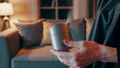 woman holding a grey portable diffuser in a living room