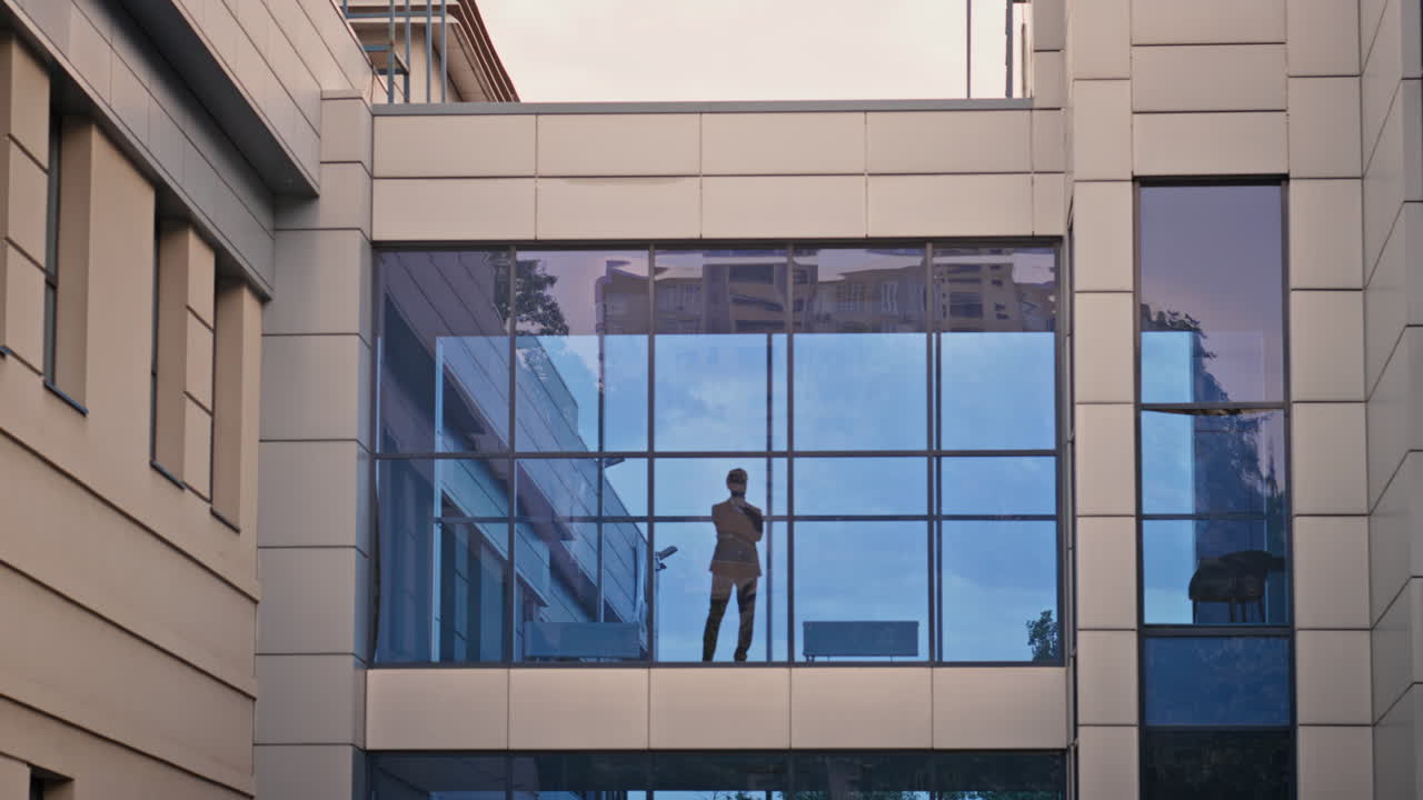 Office worker standing window contemplating city view at break. Silhouette man