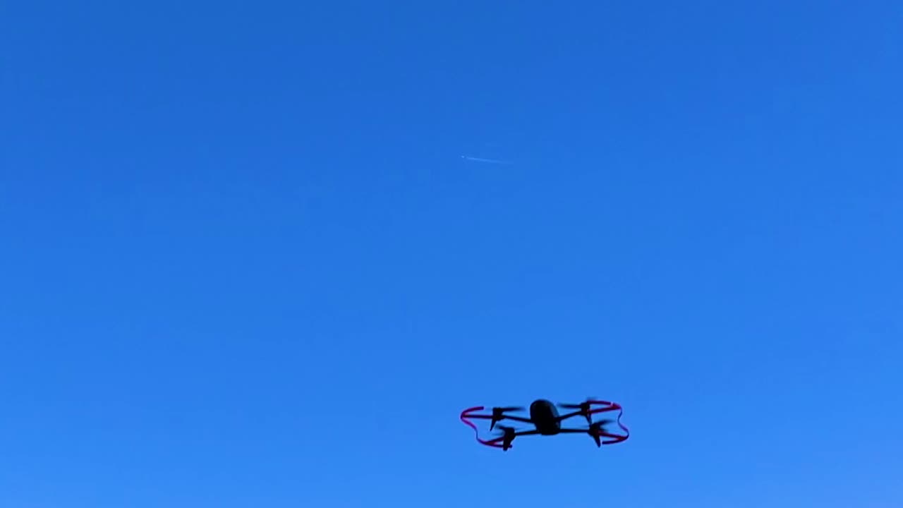 Drone performing a side flip stunt in the air with blue sky in the background
