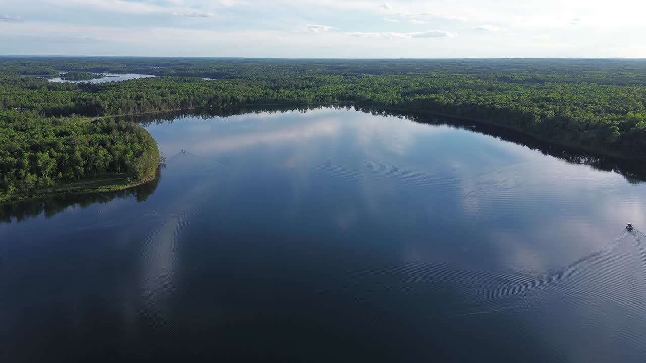 드론은 위스콘신 북부의 큰 호수 위에서 나무로 둘러싸여 총을 습니다.