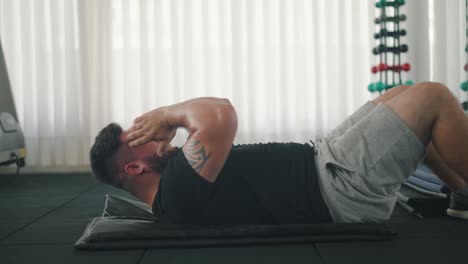 toma lateral de un joven fuerte haciendo abdominales en el gimnasio