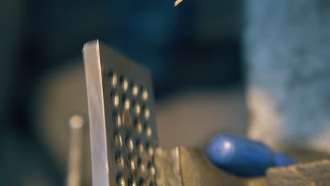 silversmith pulls wire through tool with pliers close view