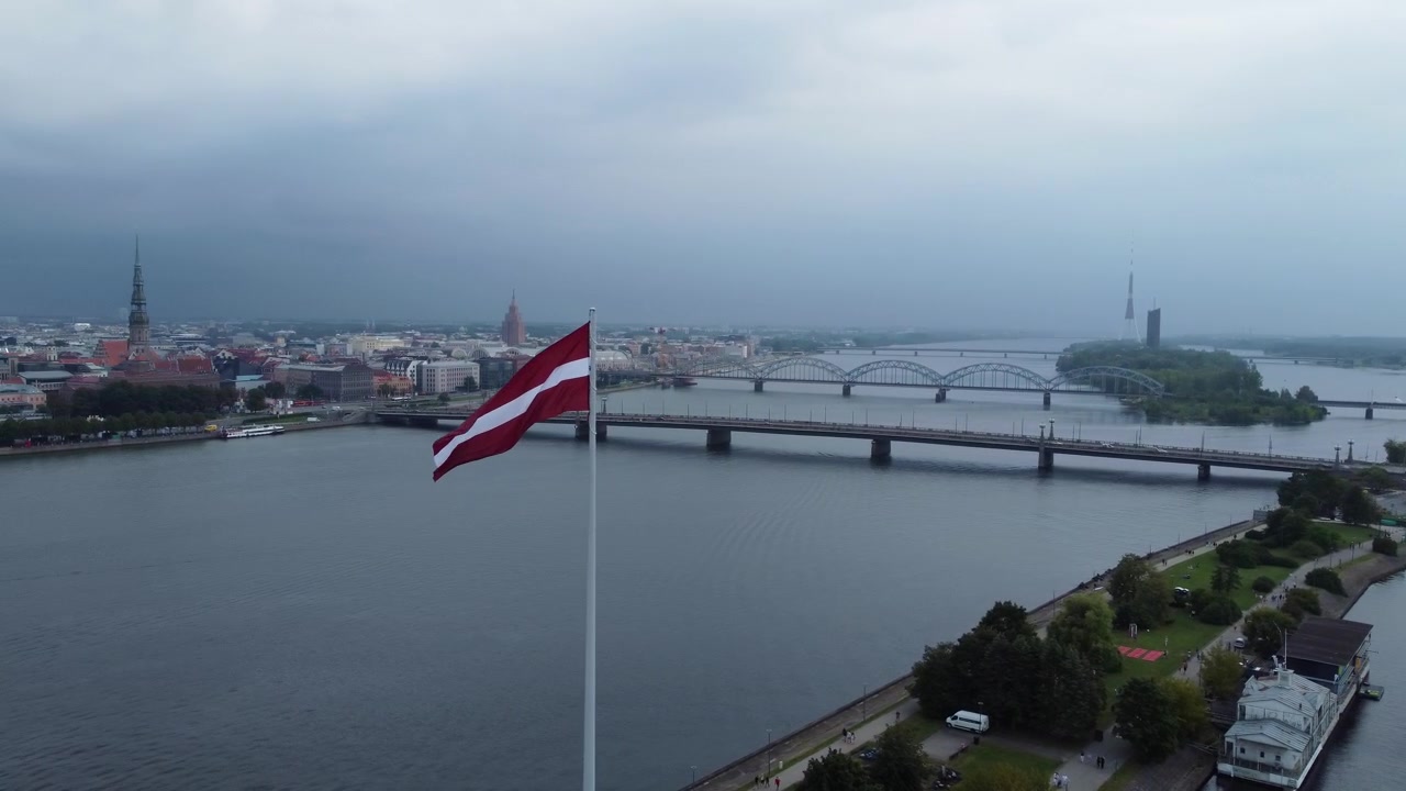 Giornata cupa e tempestosa sulla città di Riga con la bandiera della Lettonia che sventola, vista aerea orbitale.