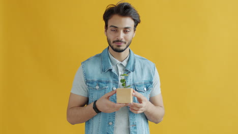 man holding small plant in wooden cube pot