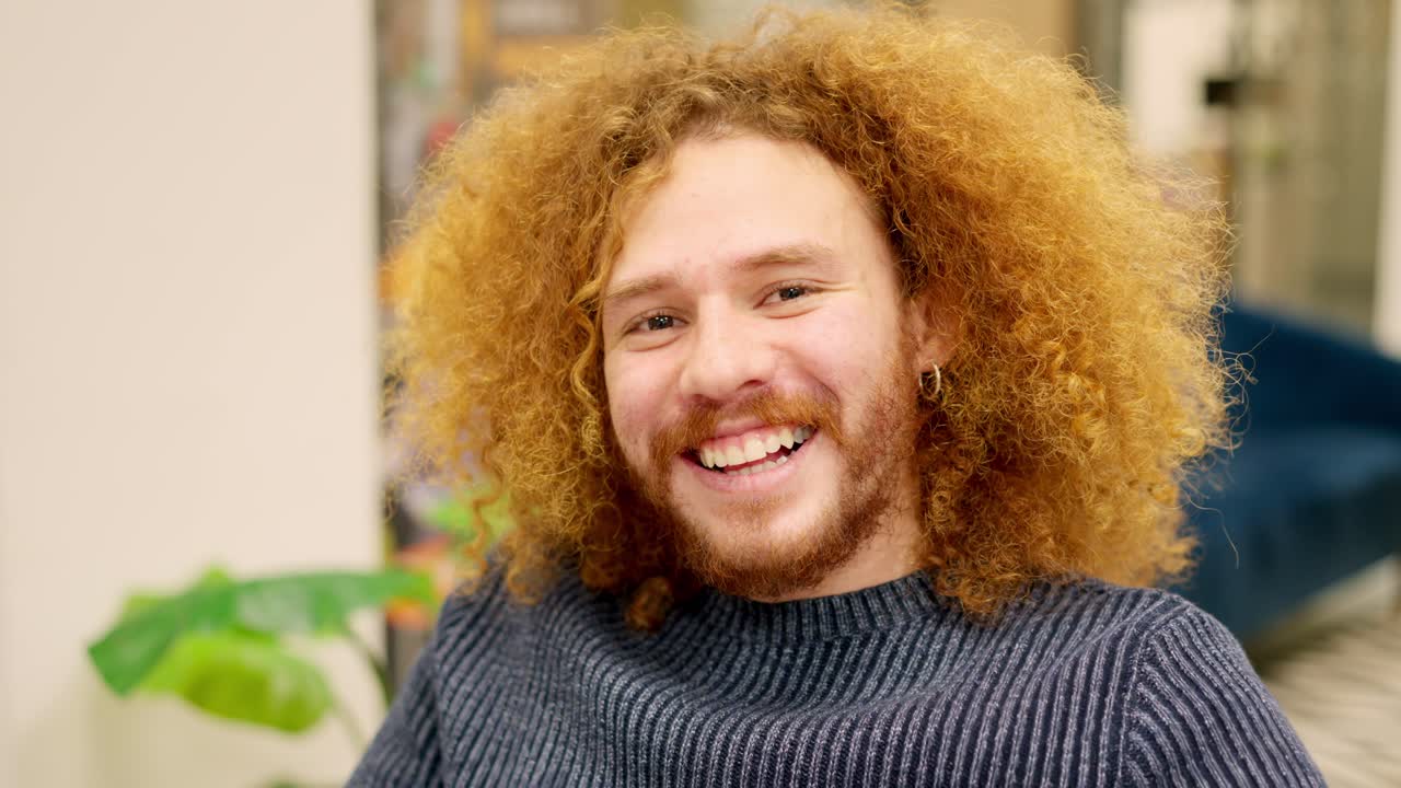 Man with curly hair smiling at camera in a coworking