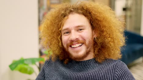 man with curly hair smiling at camera in a coworking