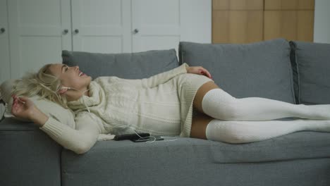 cheerful woman listening to music on sofa