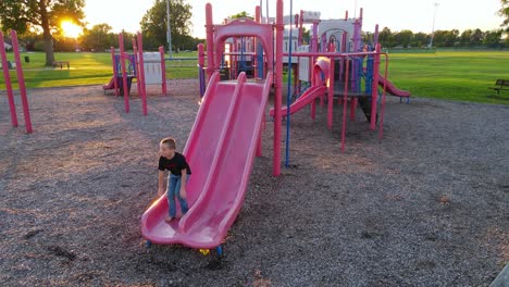 happy boy slides down slide in playground, static view
