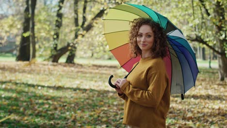 portrait of caucasian woman with colorful umbrella standing in the park.