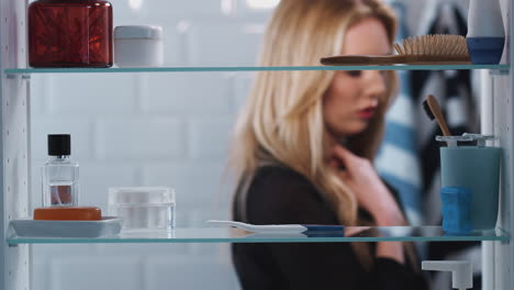 view through bathroom cabinet of anxious woman waiting for home pregnancy test result