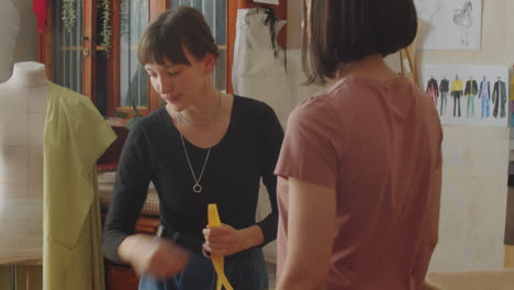 female dressmaker taking measurements of client in atelier