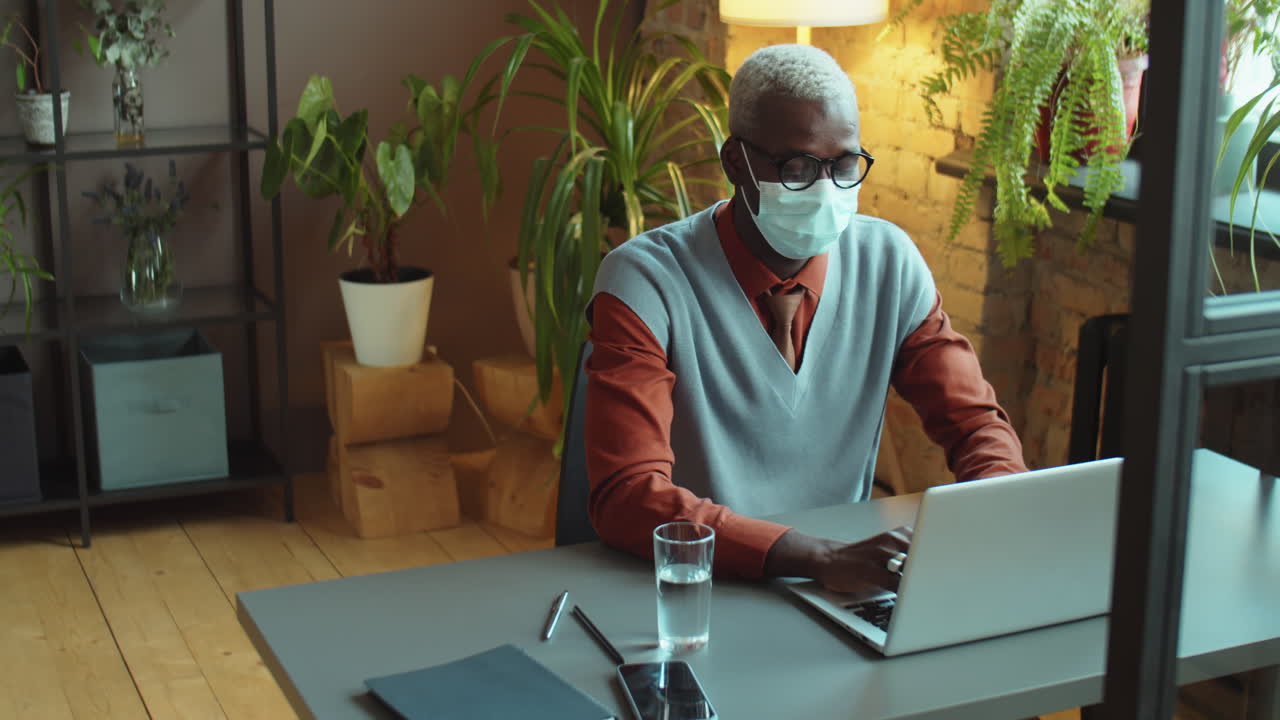 hombre de negocios negro con máscara trabajando en la oficina durante la pandemia