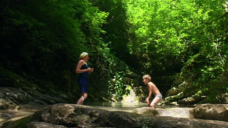 madre e hijo jugando en un arroyo del bosque