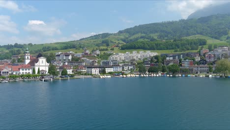 kussnacht flyover: moving over scenic water valley and village in alps mountains, switzerland, europe, drone | dramatic cinematic approaching shot of small city on vast lake and countryside