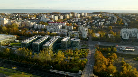 drone shot of ppnt park and apartment blocks in gdynia city with baltic sea in background - beautiful golden sunrise morning on coastal city